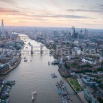 A dusk aerial view looking up the River Thames showing St Katherines Dock on the right of the image, Tower Bridge, The City of London and the Shard.